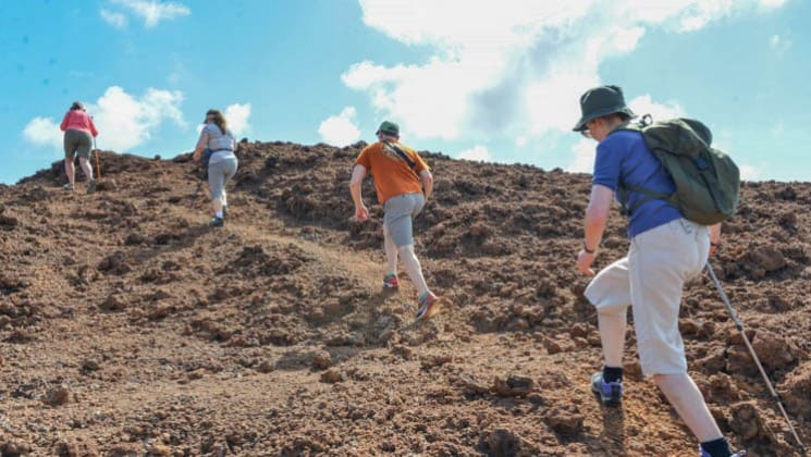 Guests from the camila luxury cruise hike up a trail at the galapagos islands