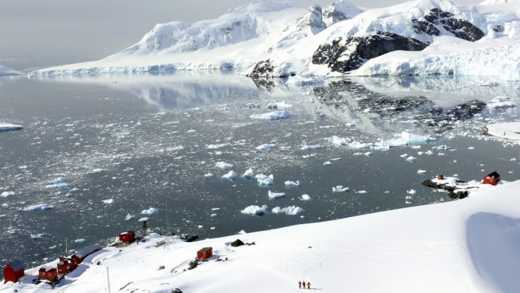 Overlooking the ocean with icebergs and a snowy vista with structures in antarctica