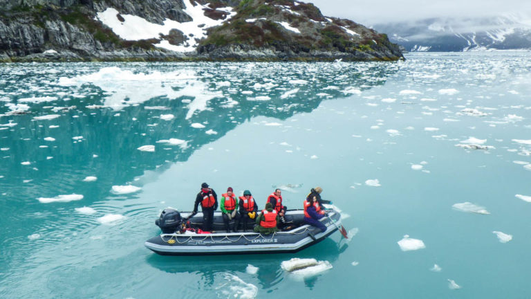 Guests floating in skiff surrounded by ice bergs in a fjord in Alaska.