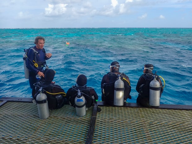 A SCUBA guide talks with a family of divers aboard a small ship