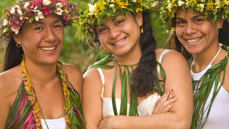 smiling indigenous pacific islands women wearing leaf and flower necklaces and head dresses
