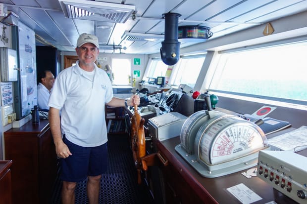 A Galapagos ship captain at the helm of a small ship