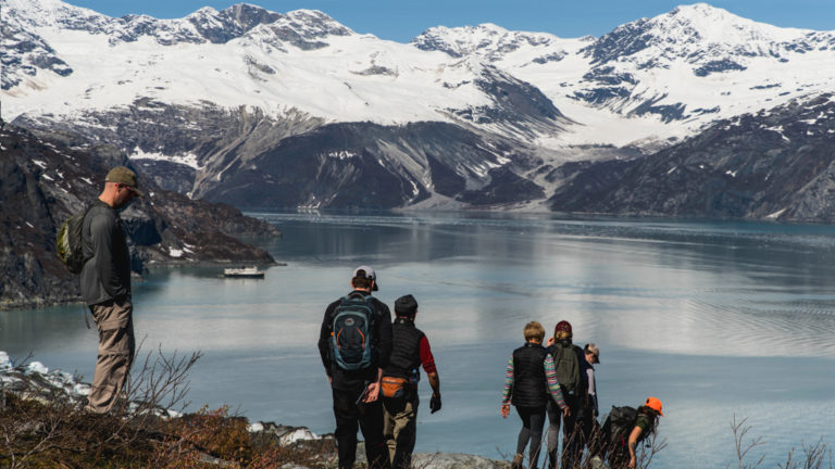 Guests Hiking Lamplugh in Glacier Bay witha view of a fjord with a glacier.