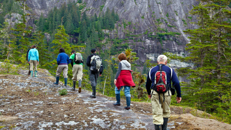 line of adventure travelers on an alaska hiking excursion along a ridge as an activity offered from their small ship cruise