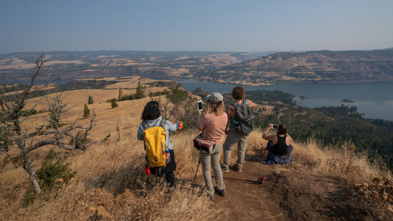 A group of hikers take photos of the sweeping view at the top of Rowena Crest on the Rivers of Adventure cruise