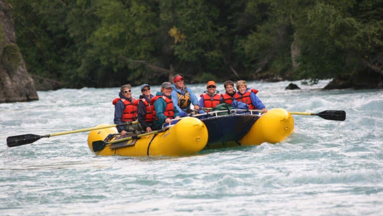 a group sits in red life jackets in a yellow river raft on the penia river while on the ultimate Alaska adventure land tour