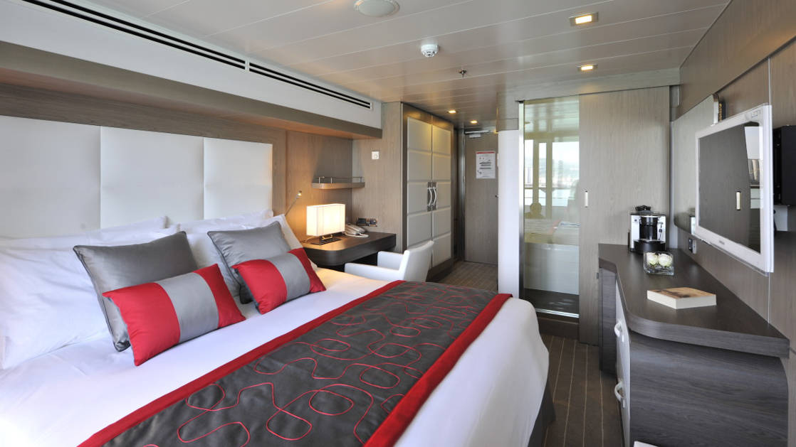 Prestige stateroom aboard Le Boreal expedition ship, showing king bed, desk & white-&-copper appointments.