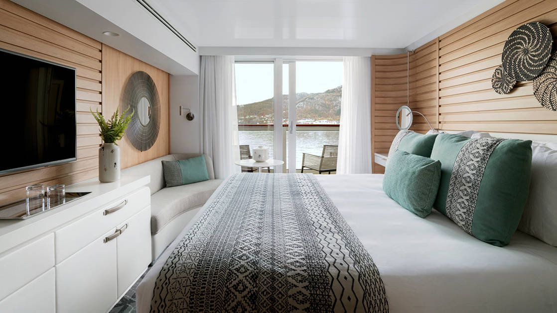 Prestige Stateroom - Decks 4, 5 & 6 aboard French expedition ship Le Champlain, with king bed, white linens, chic ethnic decor & private balcony.