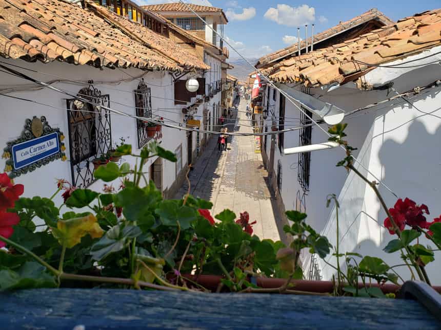 An alleyway in Cusco, Peru. Bright white exteriors with adob orange shingles on the roof.