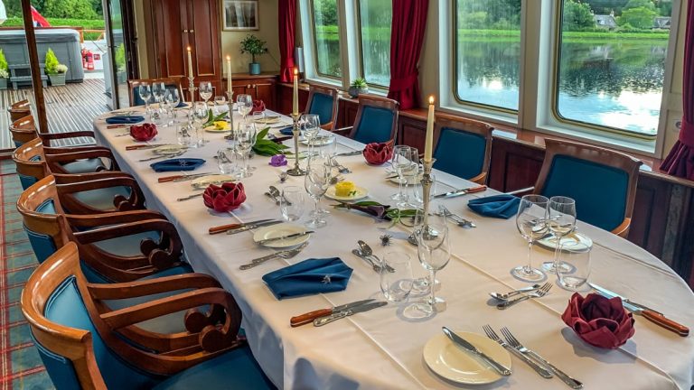 Dining table set for service with red, white & blue linens aboard Spirit of Scotland barge.