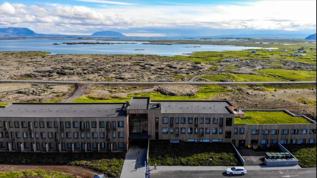 Aerial view of Fosshotel Myvatn Iceland hotel. A modern wood-paneled building sitting on a hillside overlooking the iconic lake.