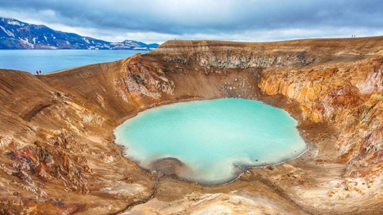 Aerial view of large tan volcanic crater with milky turquoise water in the center, seen on the Iceland Adventure: Land of Fire & Ice tour.