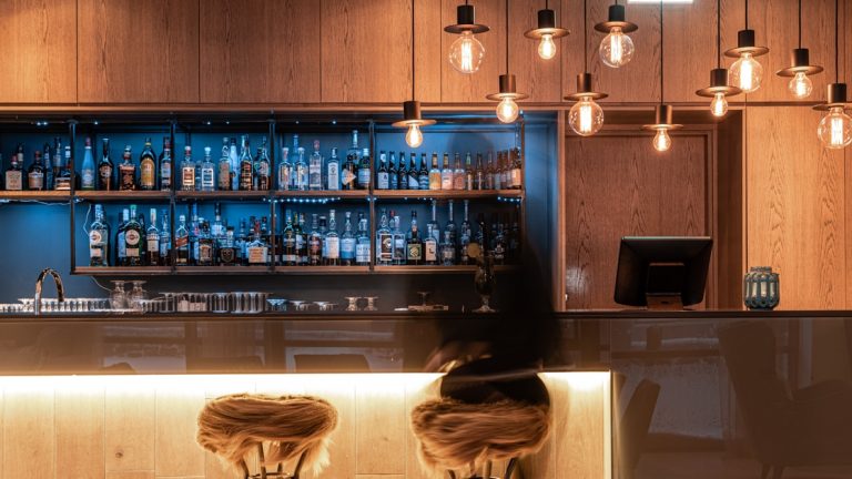 Bar at Hotel Vik i Myrdal, with contemporary style, hanging Edison bulbs, furry bar stools & dim lighting.