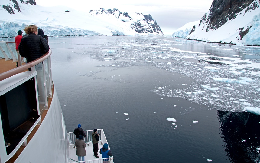 Travelers gather at the bow and on extended viewing platforms of an Antarctica ship and view the icy Antarctica landscape.