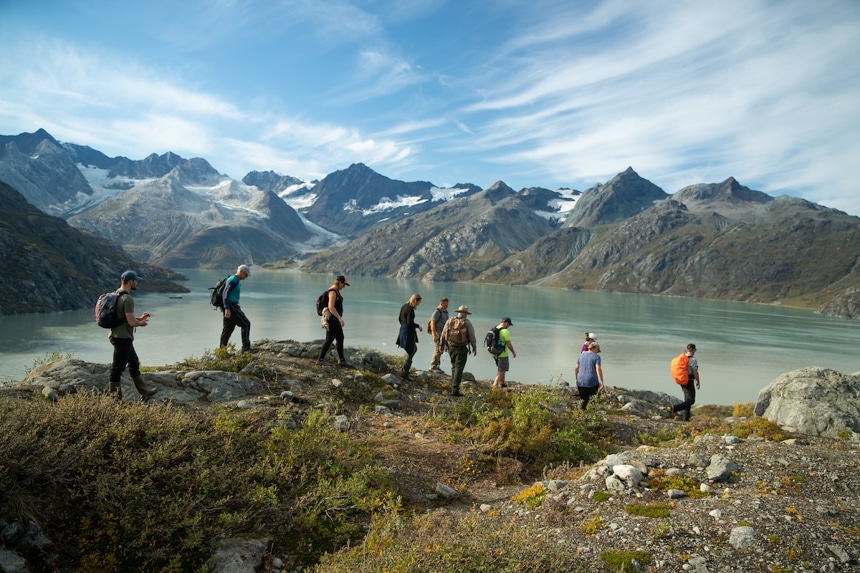 A group of hikers walk the ridgeline offering sweeping views of the mountain scape and glacier bay national park below them