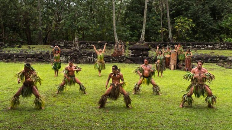 Group of Pacific Islanders dressed in native garb dance atop grass on the Under The Southern Cross: New Zealand to Melanesia cruise.