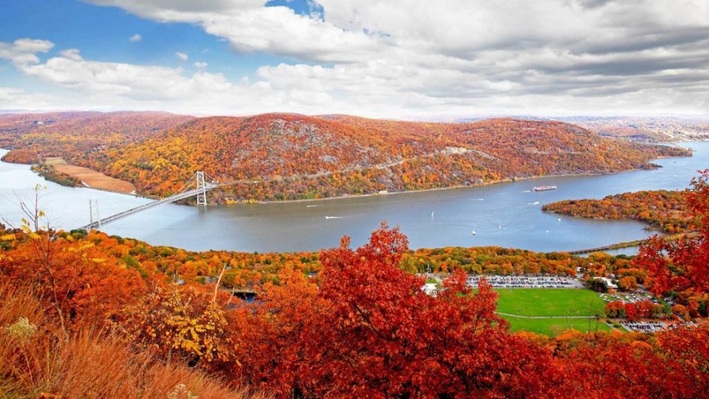 Aerial view of a bend in the Hudson River with a suspension bridge over it, seen on a Hudson River fall foliage cruise.